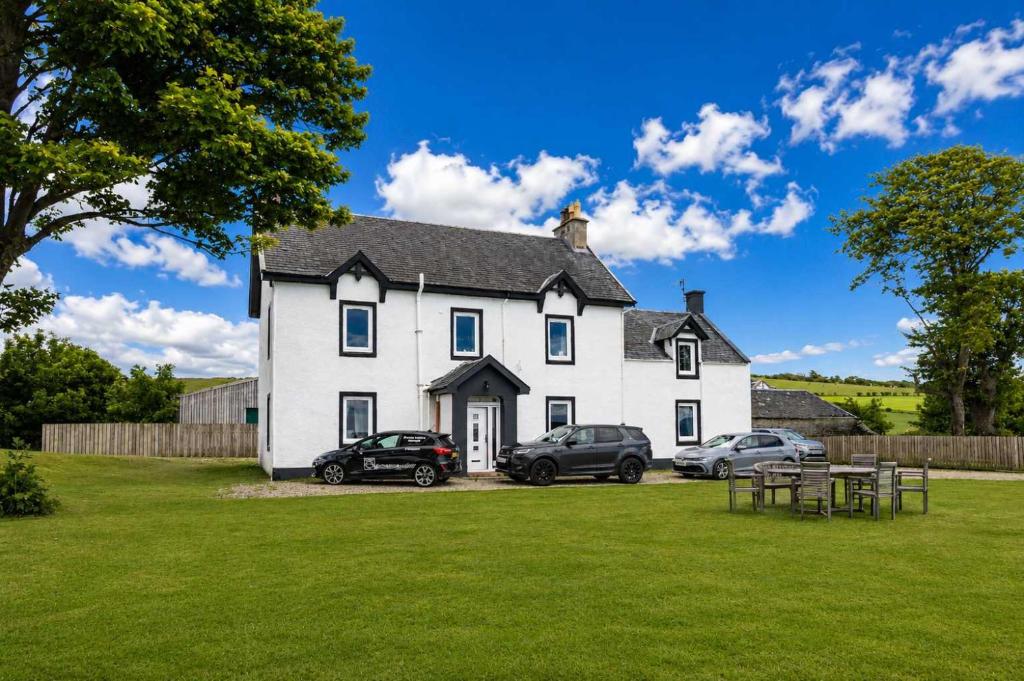 a white house with two cars parked in the yard at Dunallan Farm Cottage with Optional Hot Tub & Stunning Views in Island of Bute