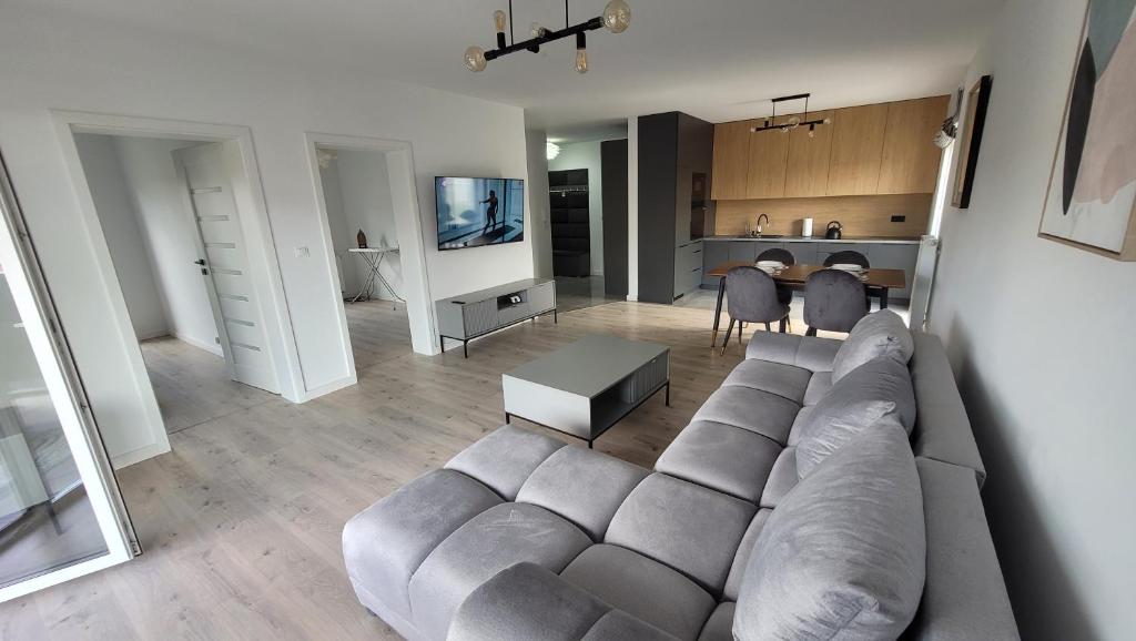 a living room with a large couch and a kitchen at Apartament Mickiewicza in Staszów