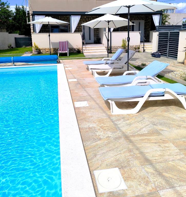 a group of chairs and umbrellas next to a swimming pool at Royal place in Nin