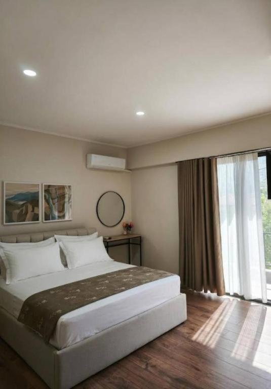 a bedroom with a large bed and a large window at Velia Rooms in Përmet