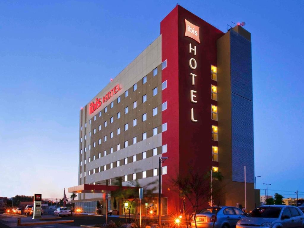a hotel building with cars parked in a parking lot at Ibis Hermosillo in Hermosillo