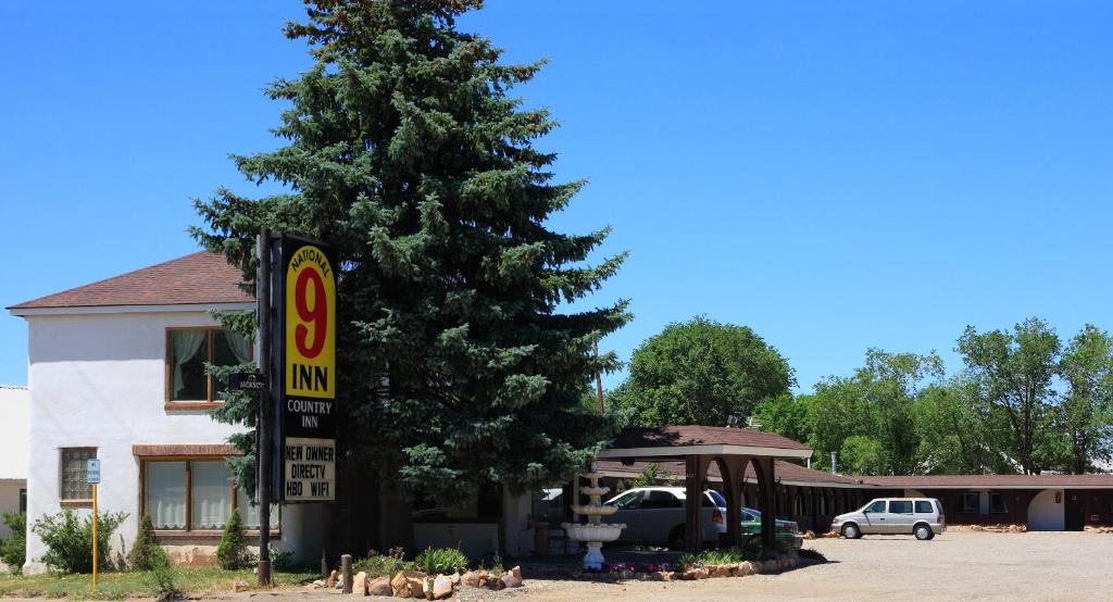 a car parked next to a tree with a sign at Country Inn Motel in Dove Creek