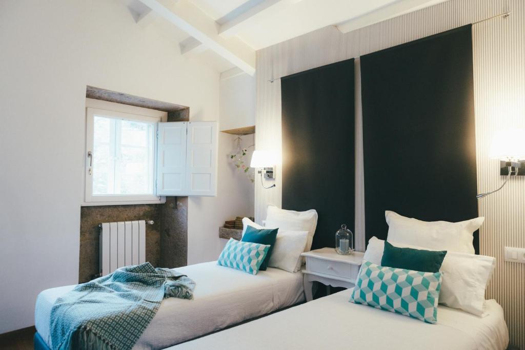 a bedroom with two beds with blue and white pillows at Apartamentos Aurelia Antica in Santiago de Compostela