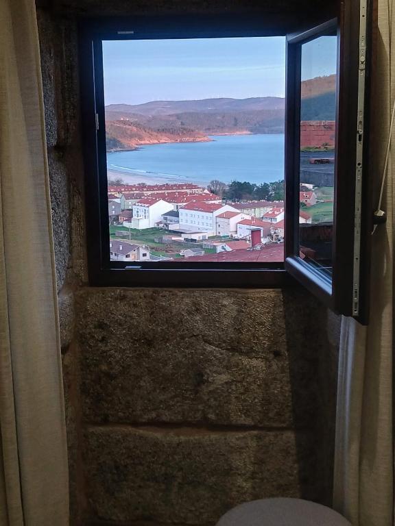 a window with a view of a body of water at Casa o Sabio in Fisterra