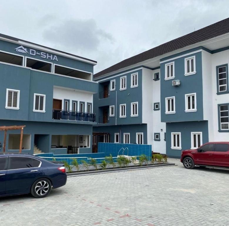 two cars parked in a parking lot in front of a building at D-SHA Apartments in Aja