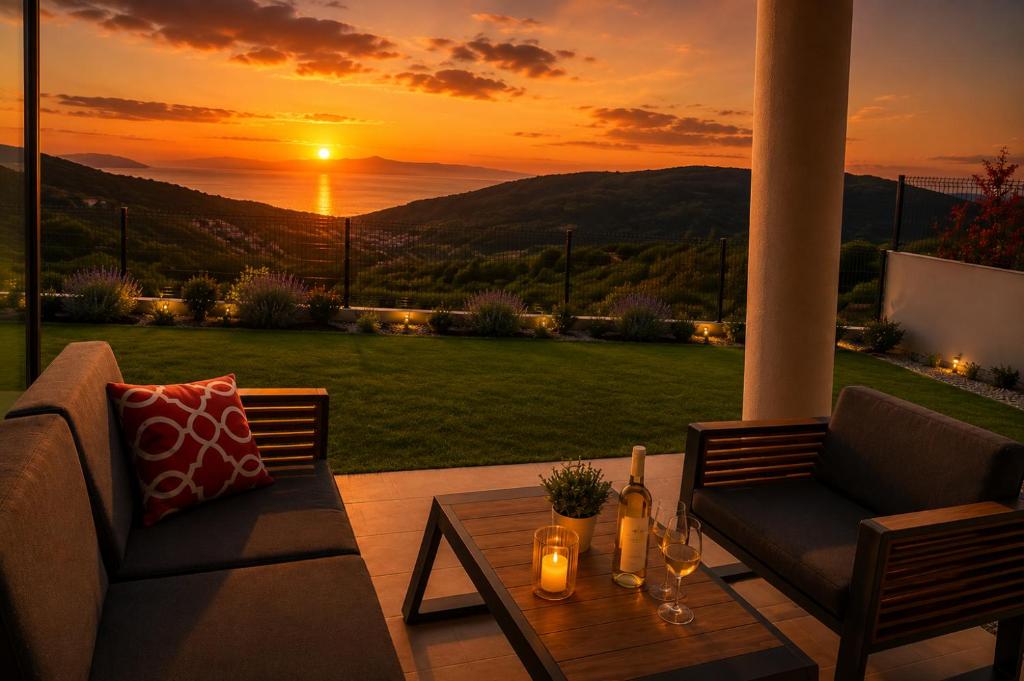 a patio with a couch and a table with a sunset at Visum Residence Labin - Luxury sea view retreat in Labin