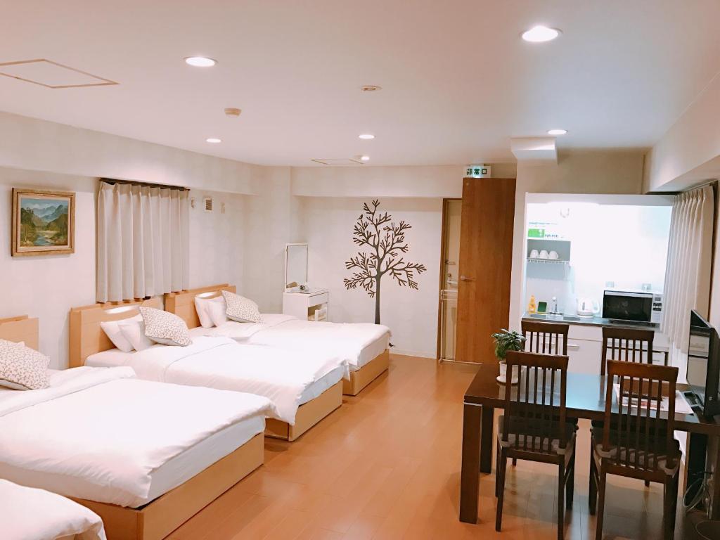 Cette chambre d'hôtel comprend 3 lits, une table et des chaises. dans l'établissement Sarangbang, à Kyoto