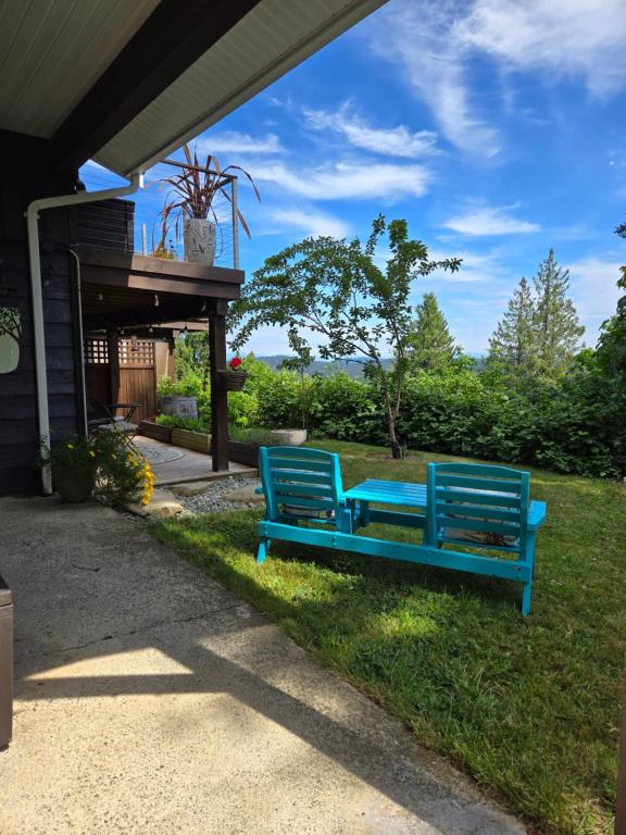 two blue benches sitting on the grass in a yard at Cozy Sanctuary in Saltspring Island