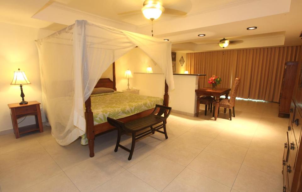 a bedroom with a canopy bed and a table and chairs at The Crown House Hotel in Philipsburg