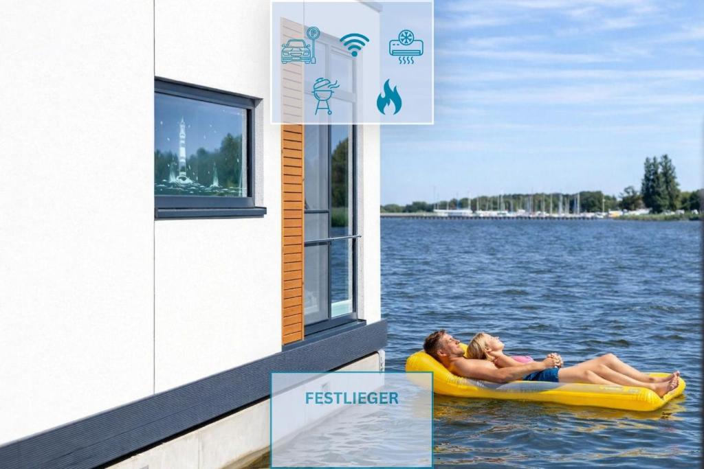 two people laying on a raft in the water at Floatinghouse Ankerplatz in Ribnitz-Damgarten