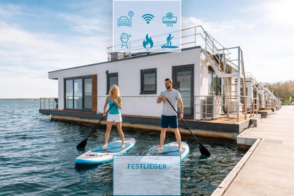 a man and woman on paddle boards in front of a house at Floatinghouse King - LP5 in Vetschau