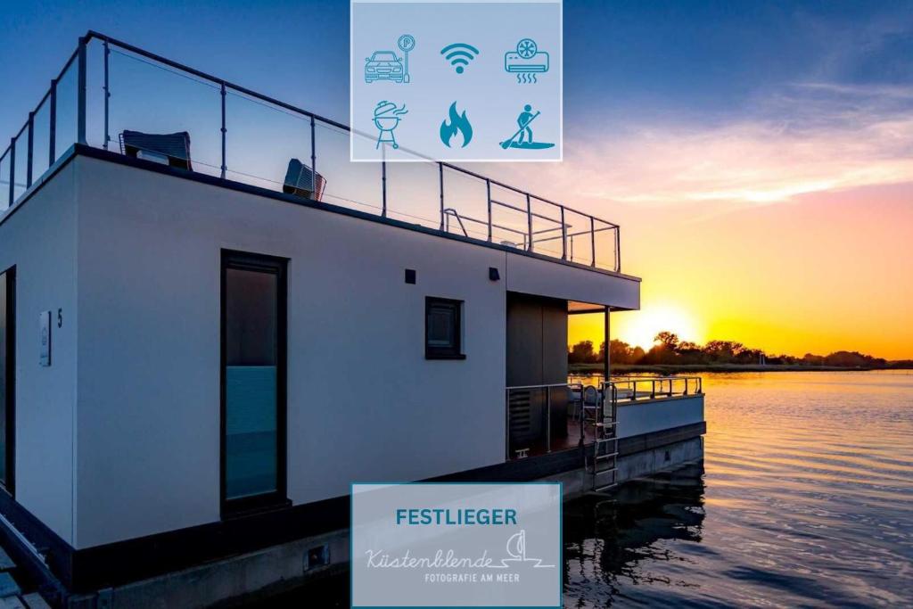 a building on the water with the sunset in the background at Floatinghouse Boddenperle in Ribnitz-Damgarten