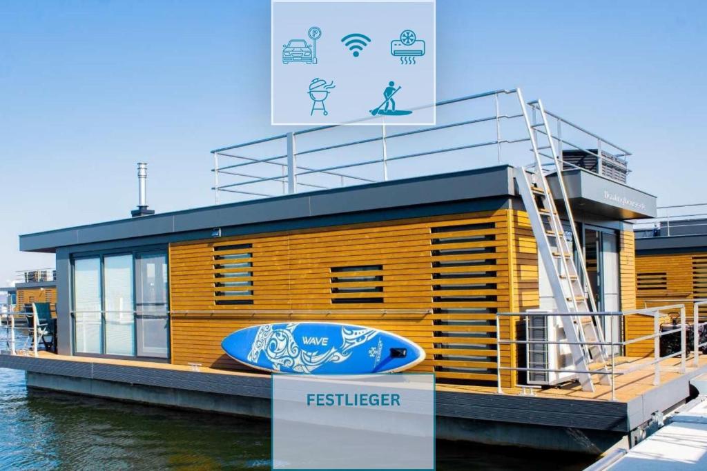 a building on the water with a surfboard on it at Floatinghouse Schatzinsel in Klitten