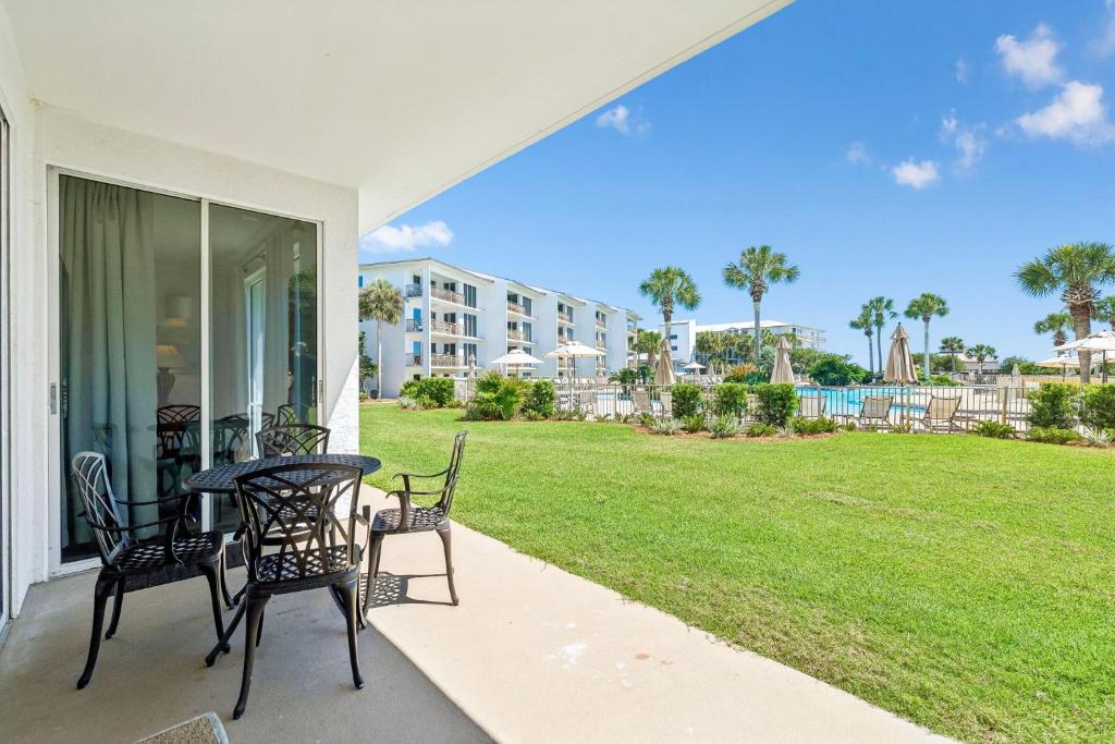 a patio with a table and chairs and a lawn at HP 124 Condo by 30A Escapes in Rosemary Beach