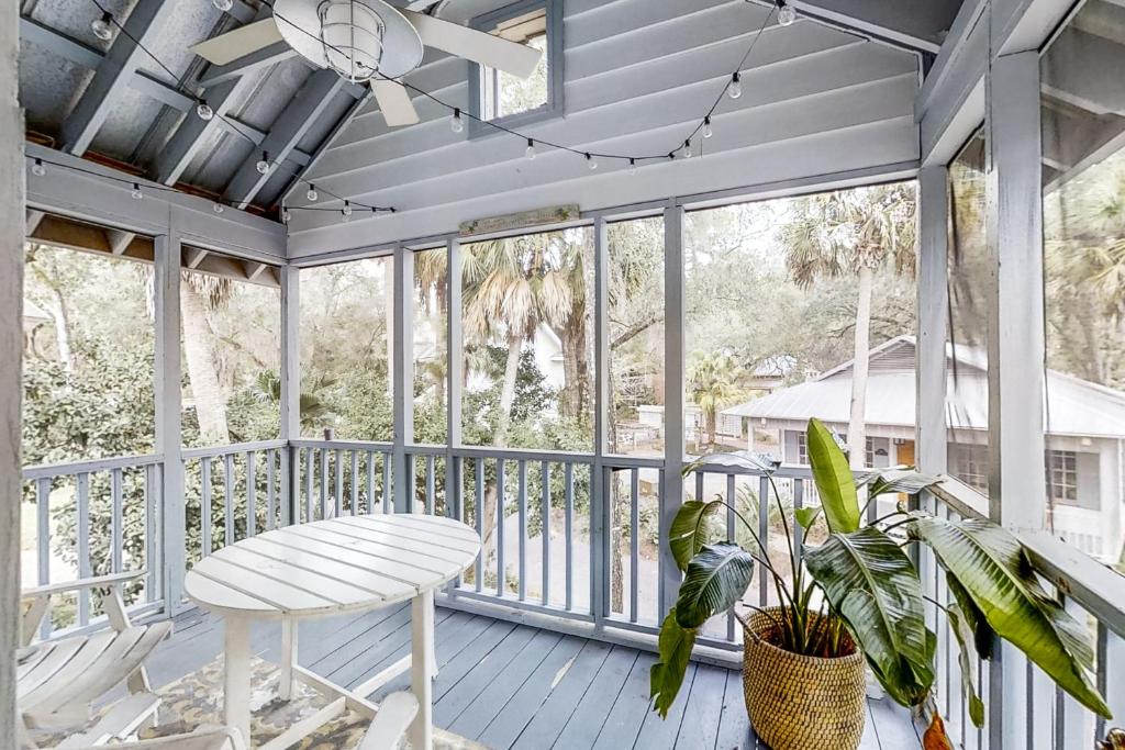 a porch with a white table and chairs and windows at Fish, Hike & Unwind! Quiet Haven in Steinhatchee in Steinhatchee