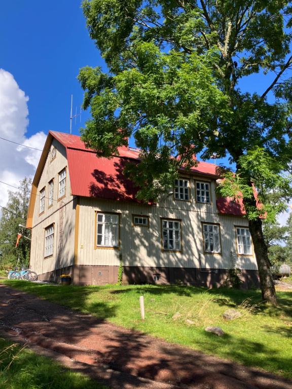 an old house with a red roof and a tree at Villa Högbo in Iniö
