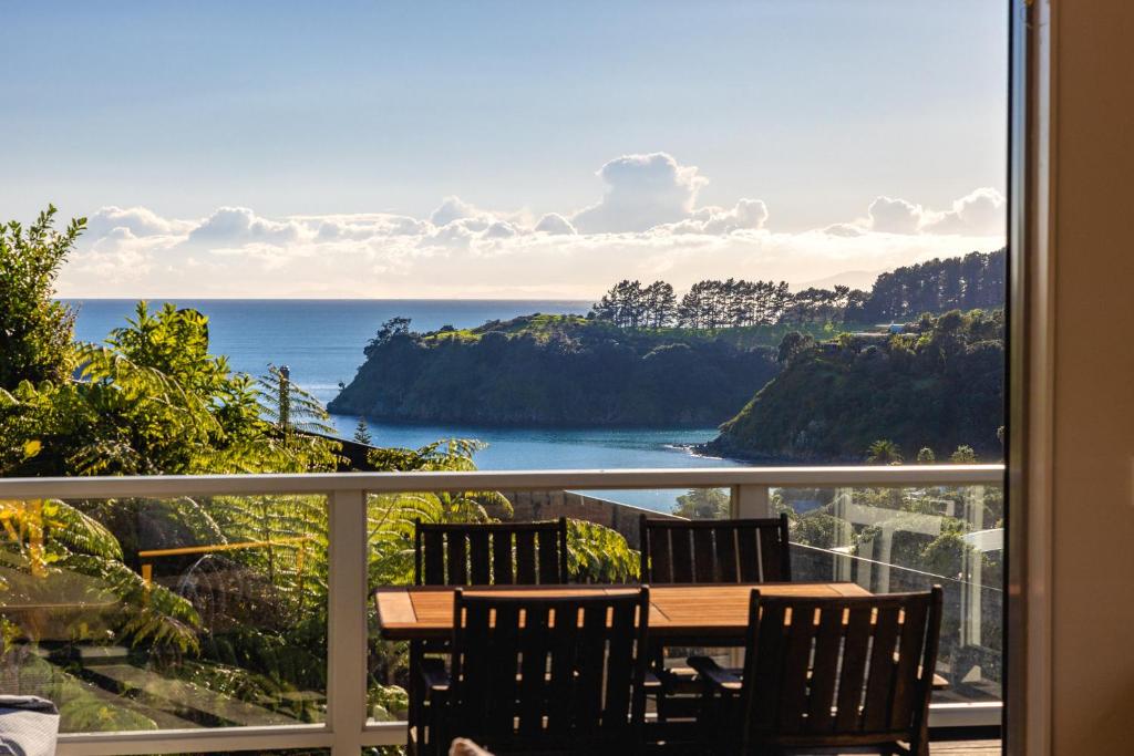 a balcony with a table and chairs and the ocean at Miro Ridge in Palm Beach in Waiheke Island