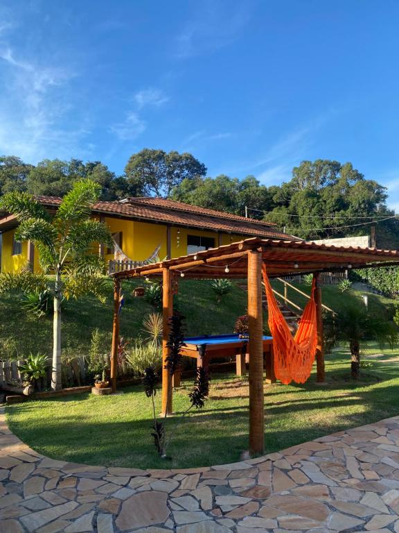 a wooden pergola with a hammock in a yard at Chácara Por do Sol in Pouso Alegre