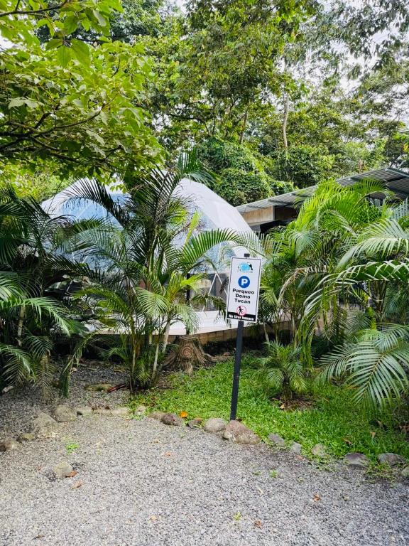 a sign sitting in the grass next to a house at Tropical Escape Domes in Guápiles