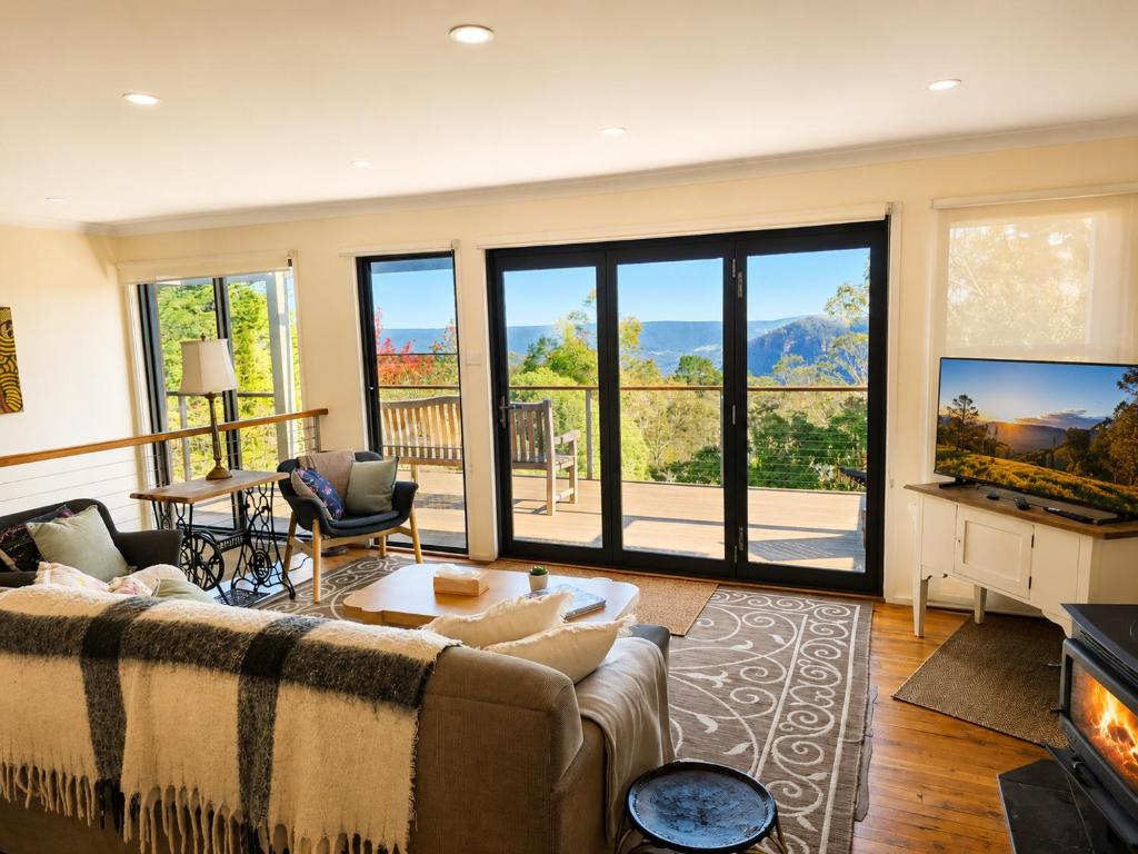 a living room with a couch and a tv at Narrow Neck Views - Peaceful 4 Bedroom Home with Stunning Views! in Katoomba