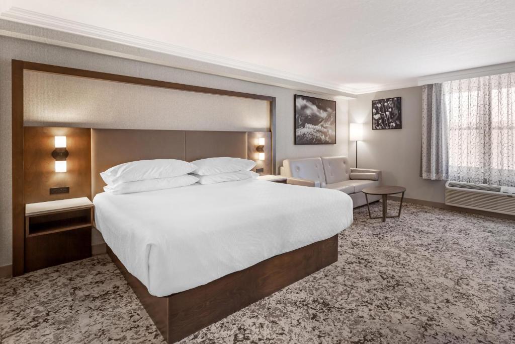 a hotel room with a large bed and a chair at Best Western PLUS The Arden Park Hotel in Stratford