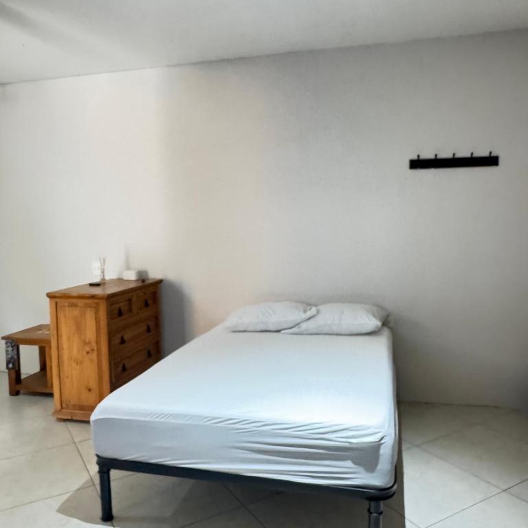 a bedroom with a white bed and a wooden dresser at Casa el palmar in Guaymas