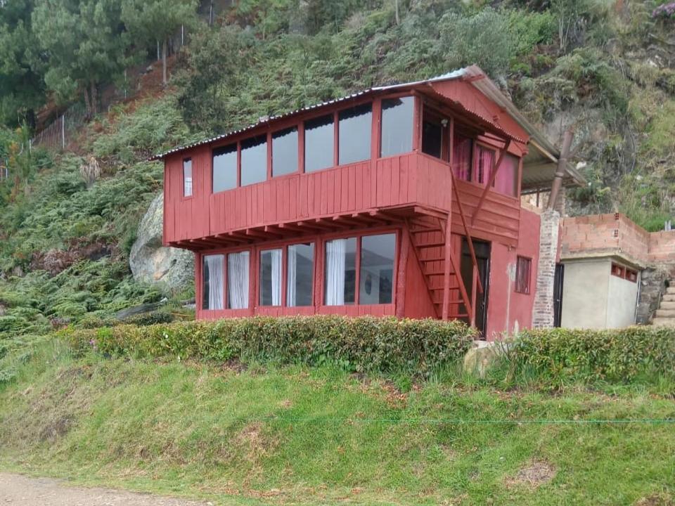 a red house on the side of a hill at Madervill Hospedaje in Aquitania
