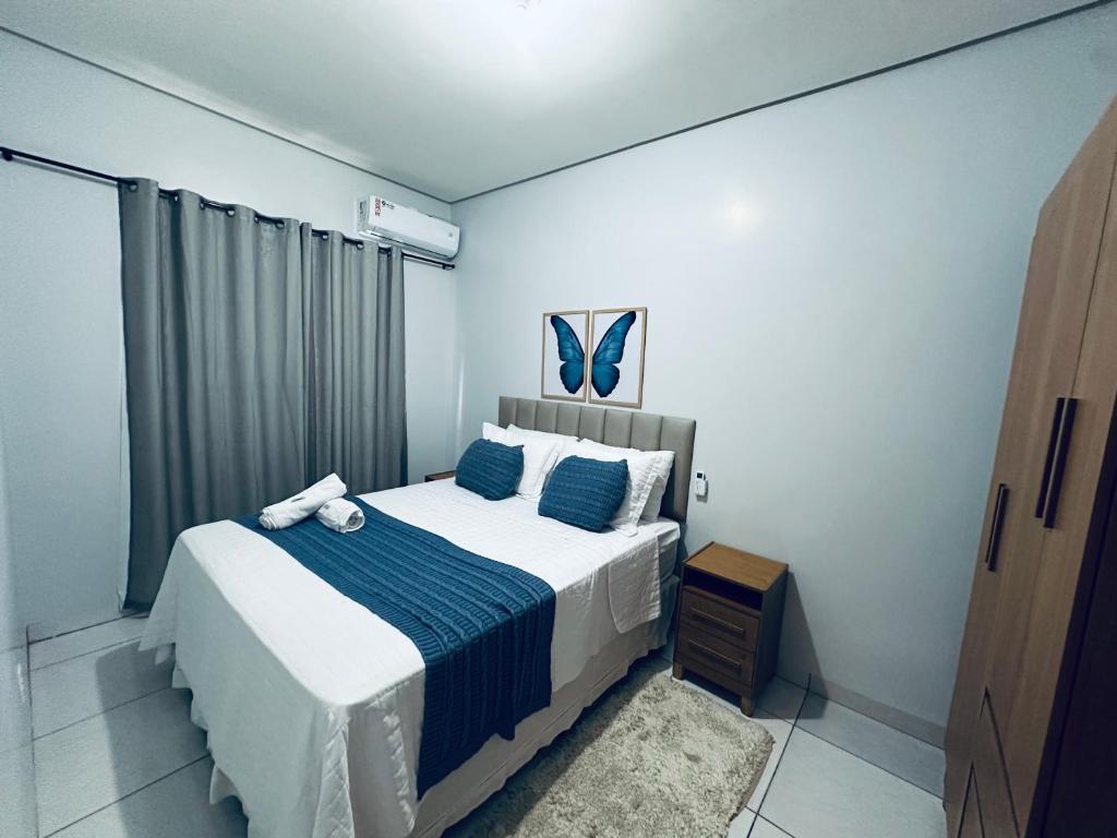 a bedroom with a bed with a blue and white blanket at Aconchego e praticidade in Mineiros