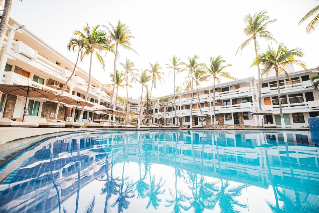 a swimming pool in front of a hotel with palm trees at Marea by Mar Paraiso Queen in Acapulco