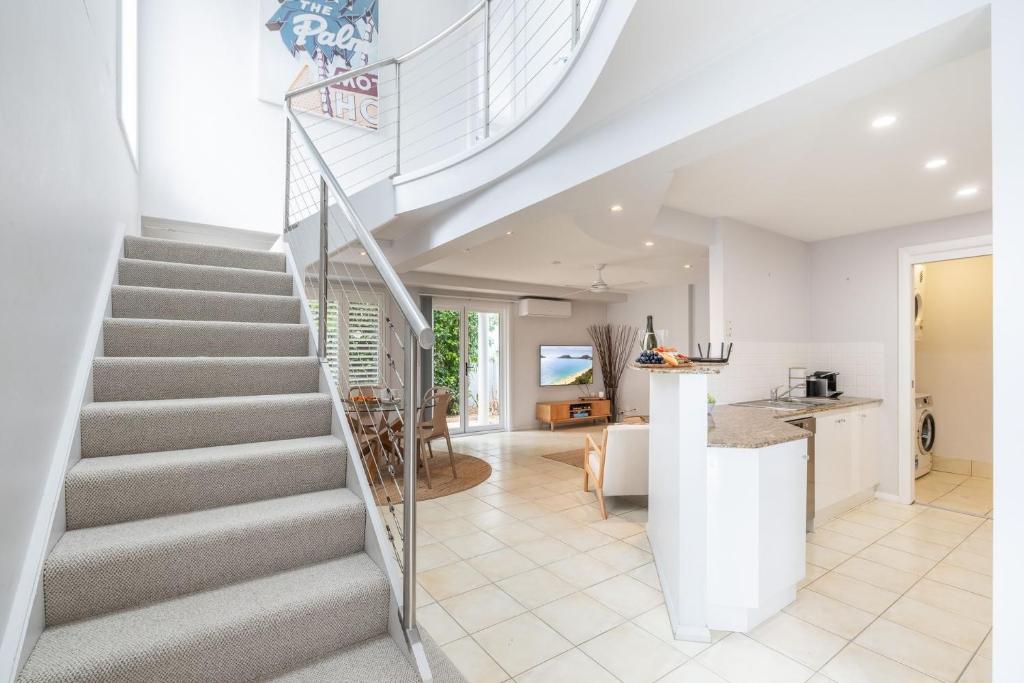 a staircase in a home with a kitchen and living room at Sandcastles 1, 8 Ala Moana Way - air conditioned townhouse with Wi-Fi and Complex Pool in Fingal Bay