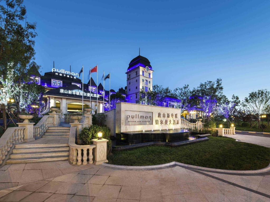 a building with a sign in a park at night at Pullman Tangshan in Tangshan