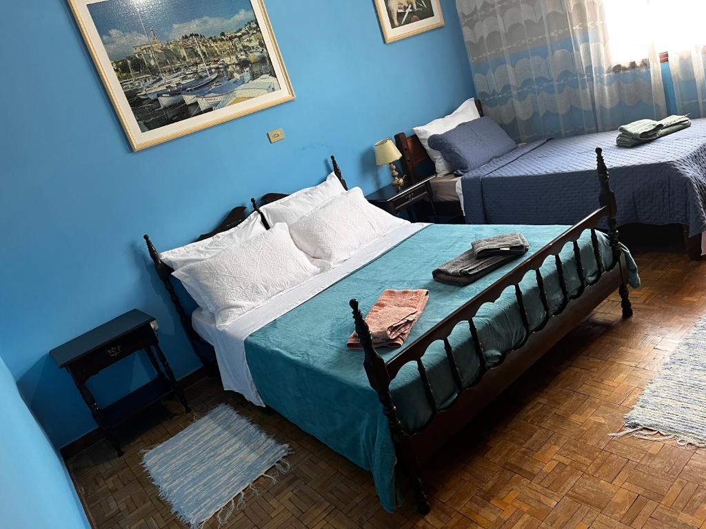 a bedroom with two beds and a blue wall at Quarto triplo - Casa Azul - Águas de São Pedro in Águas de São Pedro