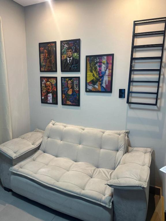 a white couch in a room with pictures on the wall at D Castro Art House in Montes Claros