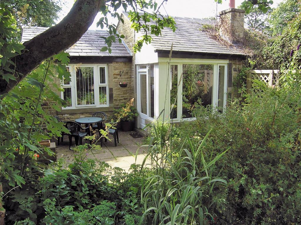 a small cottage with a table and chairs in a garden at Belgravia Cottage in Skipton