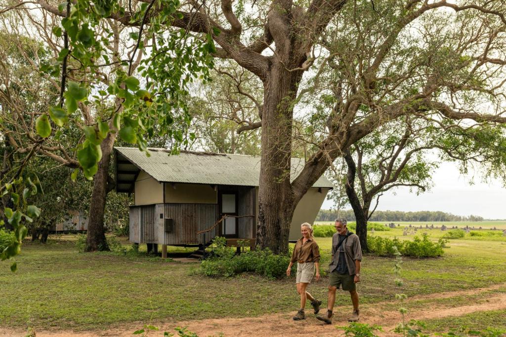 a man and a woman walking in front of a tree at Bamurru Plains in Point Stuart