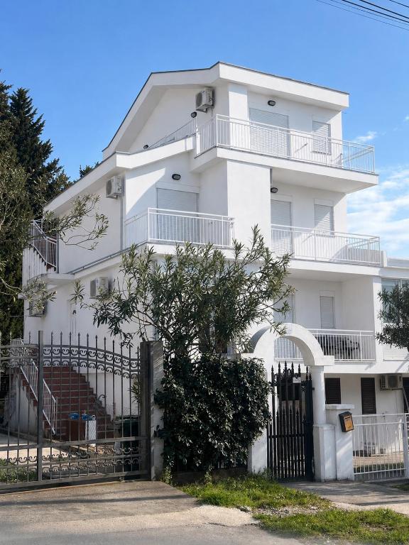 a white building with a fence in front of it at Navora Apartmani in Sutomore