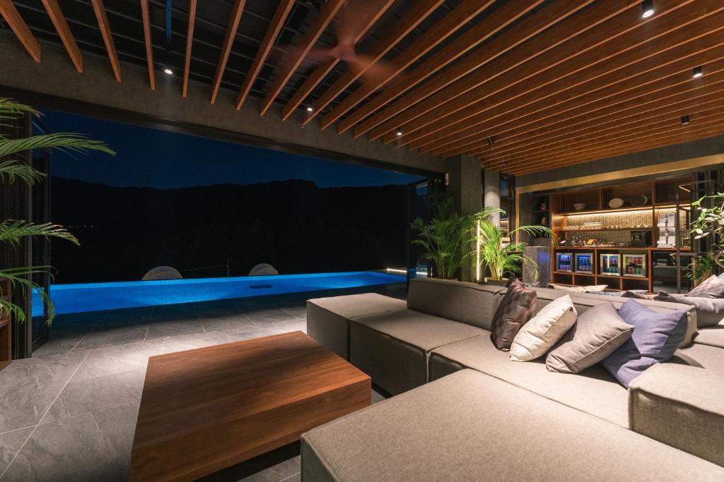 a living room with a couch and a swimming pool at The ACONCAGUA RESORTS in Minami Aso