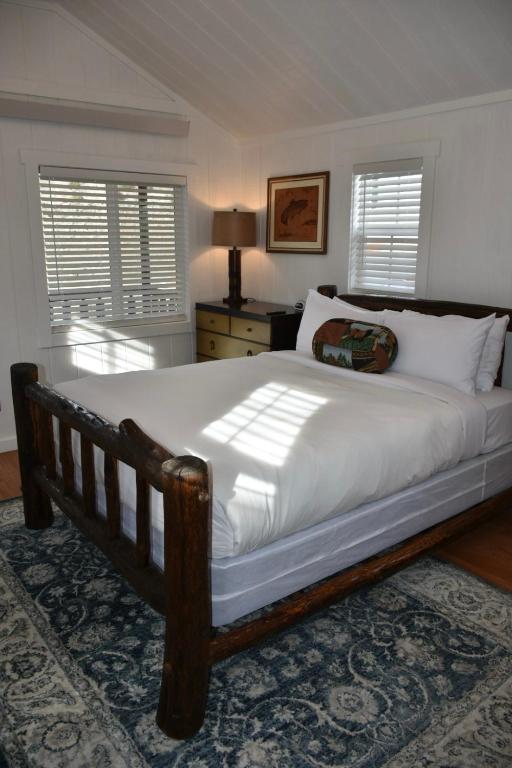 a bedroom with a large bed with white sheets at Tiny Yellowstone Riverside Cabin in Gardiner