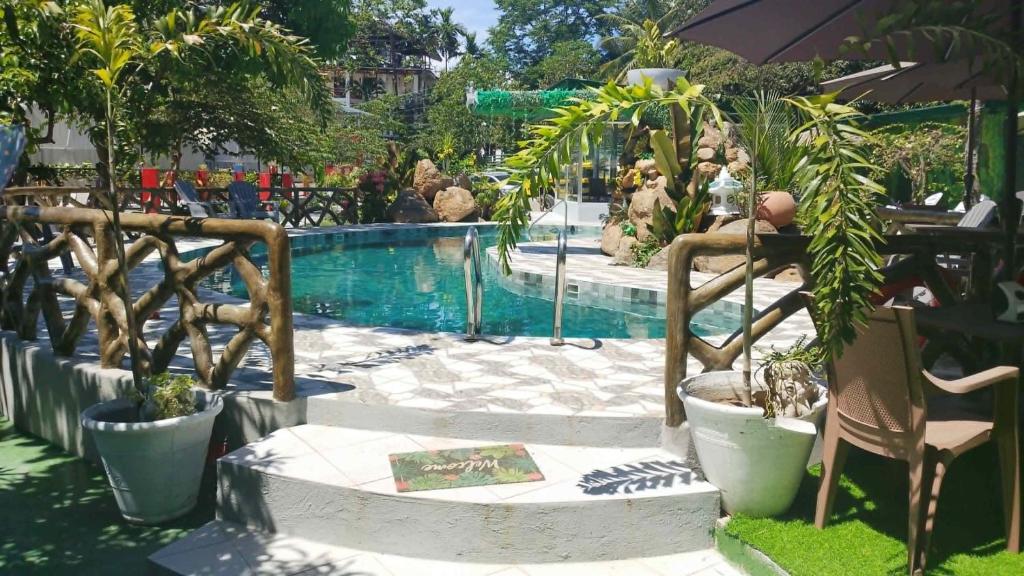 a resort with a pool with plants and a chair at GIARDINO ROMANTICO in Dumaguete
