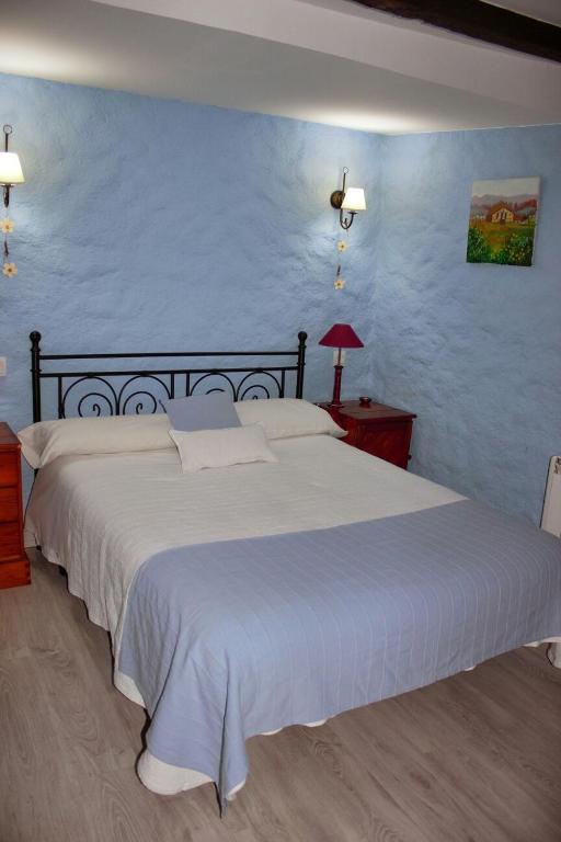 Un dormitorio con una gran cama blanca con una pared azul. en Casa Angel, en Sequeros