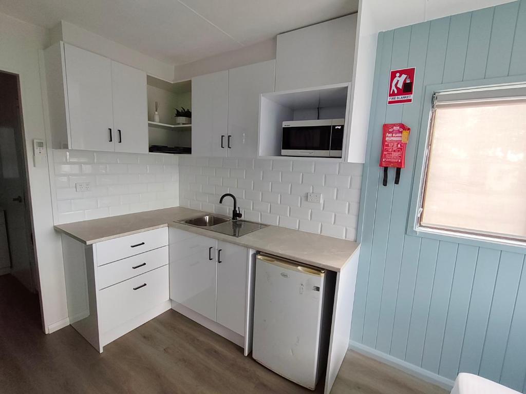 a small kitchen with white cabinets and a sink at Highlander Van Village in Armidale