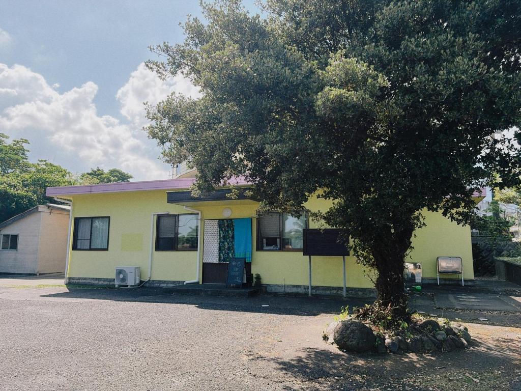 a yellow house with a tree in front of it at Oyado SORARURI in Yakushima