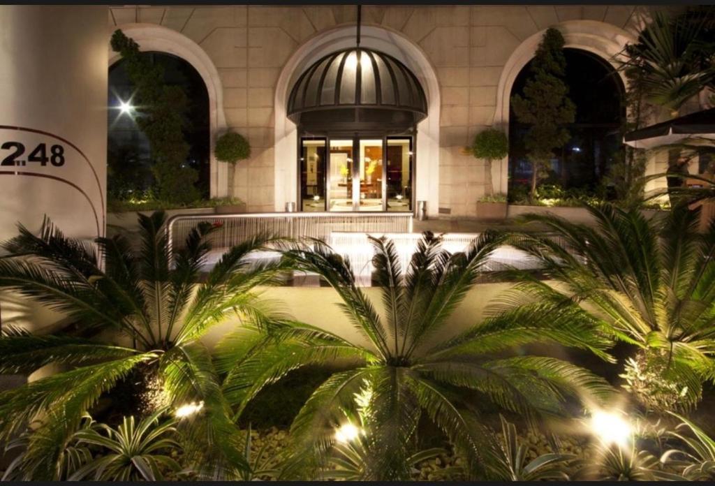 a building with palm trees in front of a store at Apart Hotel Itaim Bibi in São Paulo