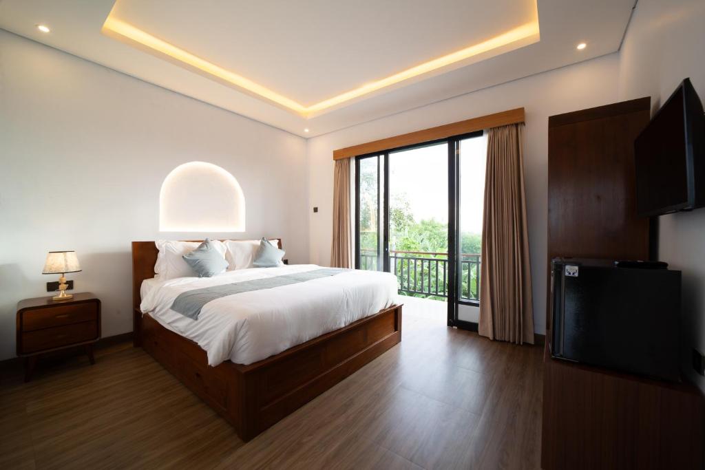 a bedroom with a bed and a tv and a balcony at Lunaire Guest House in Tabanan