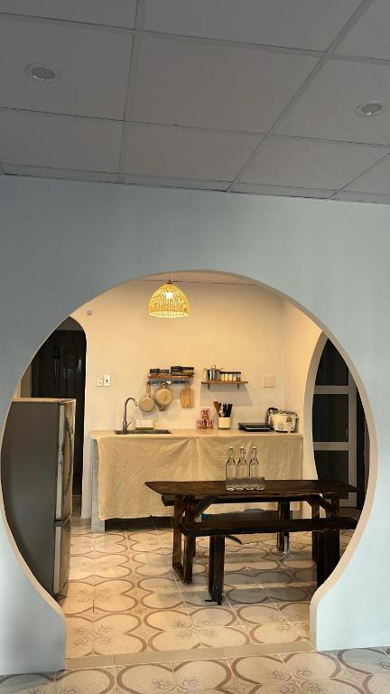 a room with a table and a kitchen with a refrigerator at Nồm House in Nha Trang