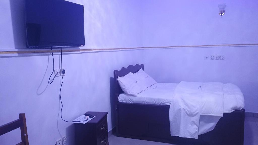 a small bedroom with a bed and a flat screen tv at Sky Blue Guest House Buea in Buea