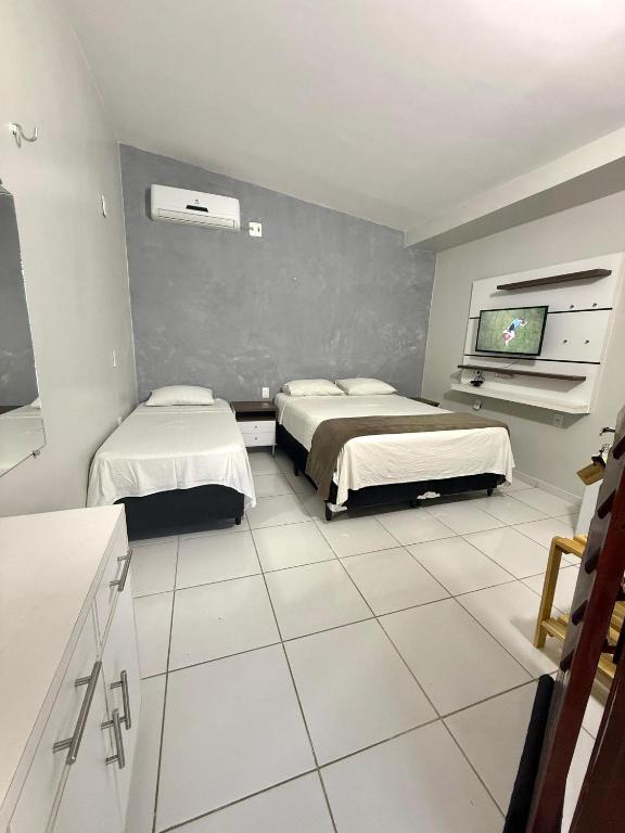 a room with two beds and a flat screen tv at Suíte Brisa Mar Villa brisa icaraizinho in Amontada
