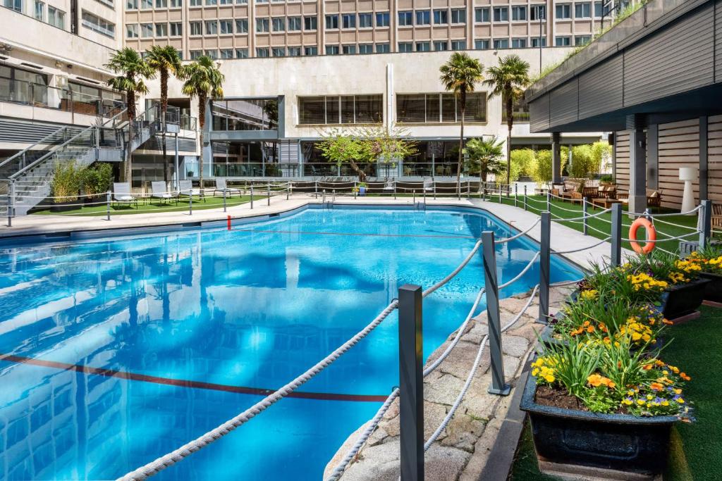 a large blue swimming pool in front of a building at Meliá Castilla in Madrid