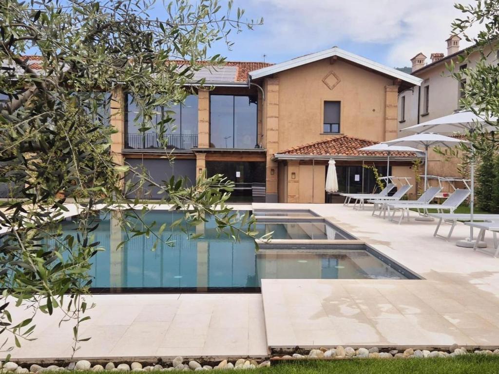 a villa with a swimming pool in front of a house at Elegant suite with shared pool in Adro
