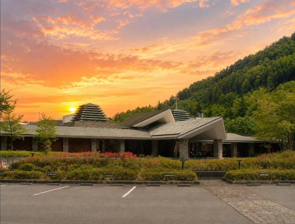 a building in a parking lot with a sunset in the background at LiVEMAX Golf Club Tochigi in Kanuma